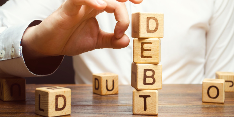 man knocking down blocks spelling debt